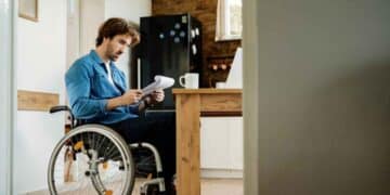 Hombre en silla de ruedas revisa documentos tras la sentencia del Supremo que prohíbe compatibilizar la pensión de incapacidad permanente absoluta con un trabajo cotizado.