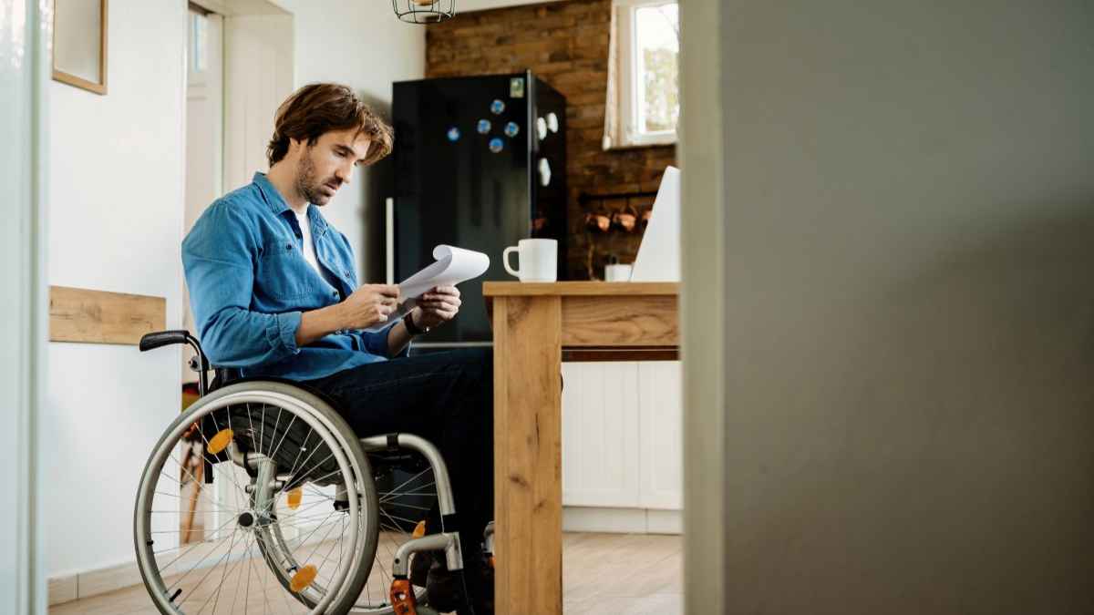 Hombre en silla de ruedas revisa documentos tras la sentencia del Supremo que prohíbe compatibilizar la pensión de incapacidad permanente absoluta con un trabajo cotizado.