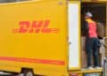 Repartidor de DHL descargando paquetes de una furgoneta amarilla, imagen ilustrativa de la estafa de SMS falsos que suplantan a la empresa