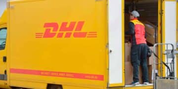 Repartidor de DHL descargando paquetes de una furgoneta amarilla, imagen ilustrativa de la estafa de SMS falsos que suplantan a la empresa