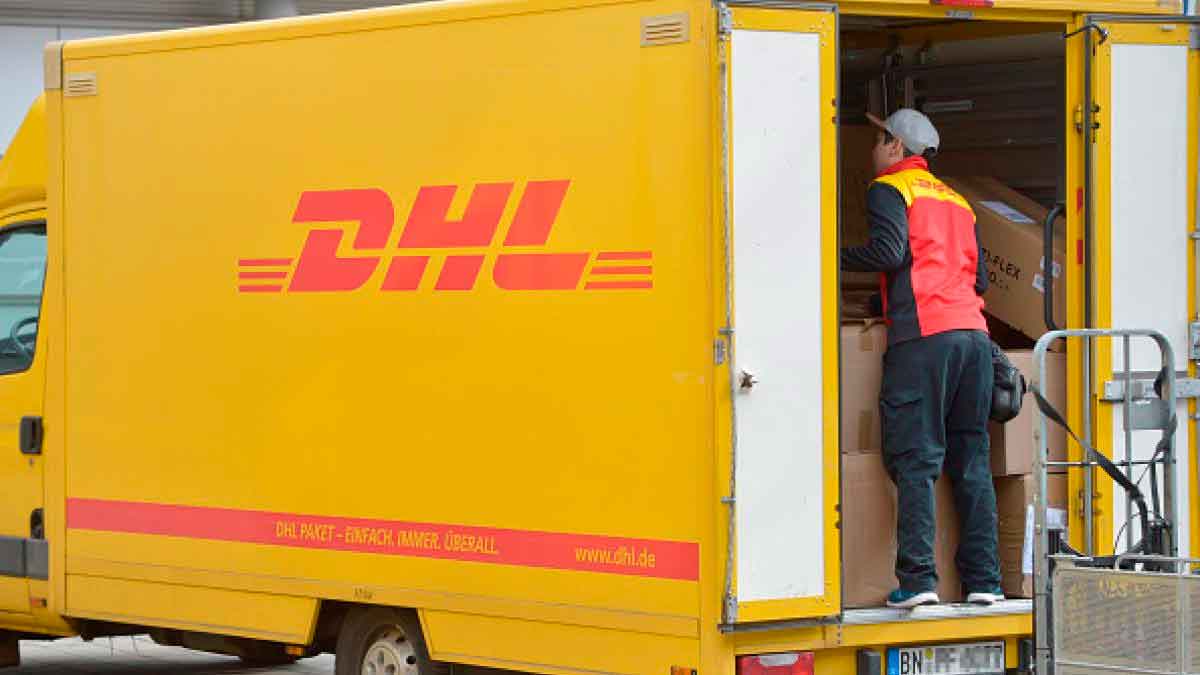 Repartidor de DHL descargando paquetes de una furgoneta amarilla, imagen ilustrativa de la estafa de SMS falsos que suplantan a la empresa