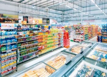 Pasillo de supermercado español repleto de productos y cámaras de congelados, antes de la liquidación total por cierre masivo