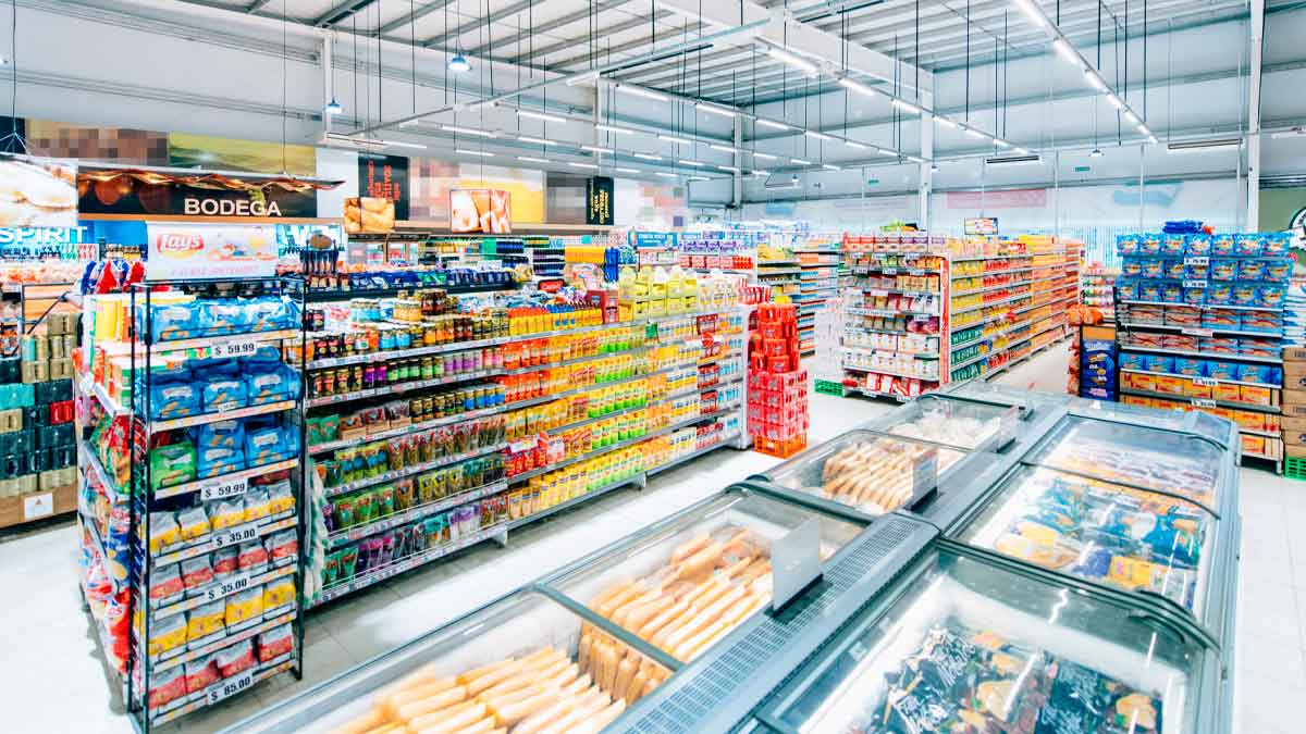 Pasillo de supermercado español repleto de productos y cámaras de congelados, antes de la liquidación total por cierre masivo