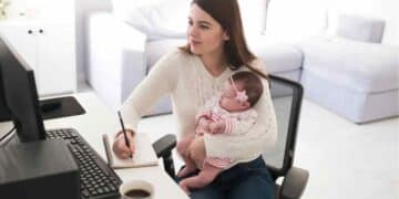 Madre autónoma teletrabajando con su bebé en brazos, ejemplo de las ayudas de maternidad 2025 que ATA reclama reforzar.