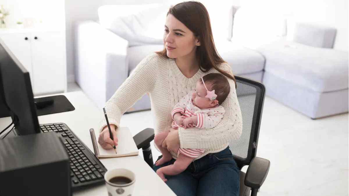 Madre autónoma teletrabajando con su bebé en brazos, ejemplo de las ayudas de maternidad 2025 que ATA reclama reforzar.