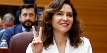 Isabel Díaz Ayuso, presidenta de la Comunidad de Madrid, gesticulando con el signo de victoria en una sesión parlamentaria.