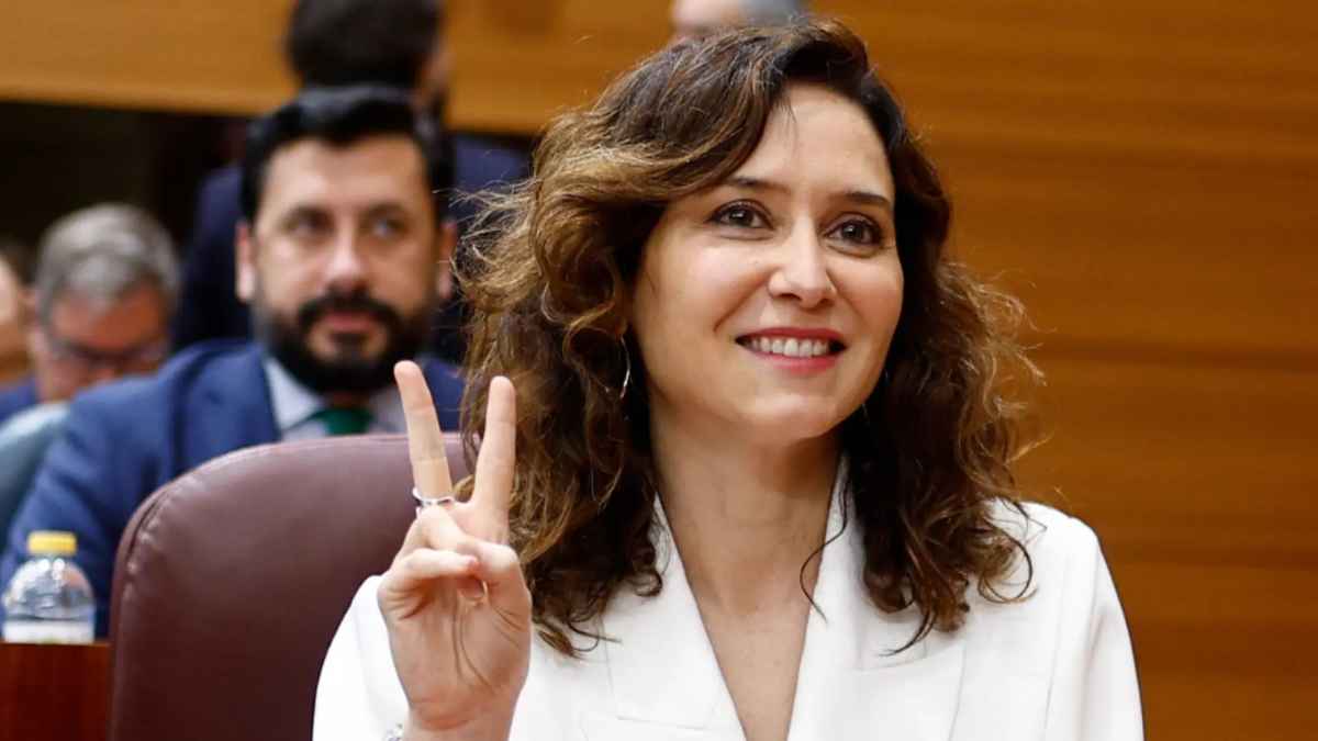 Isabel Díaz Ayuso, presidenta de la Comunidad de Madrid, gesticulando con el signo de victoria en una sesión parlamentaria.