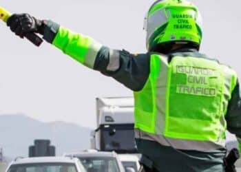 Agente de la Guardia Civil de Tráfico señalizando con banderín amarillo en carretera.