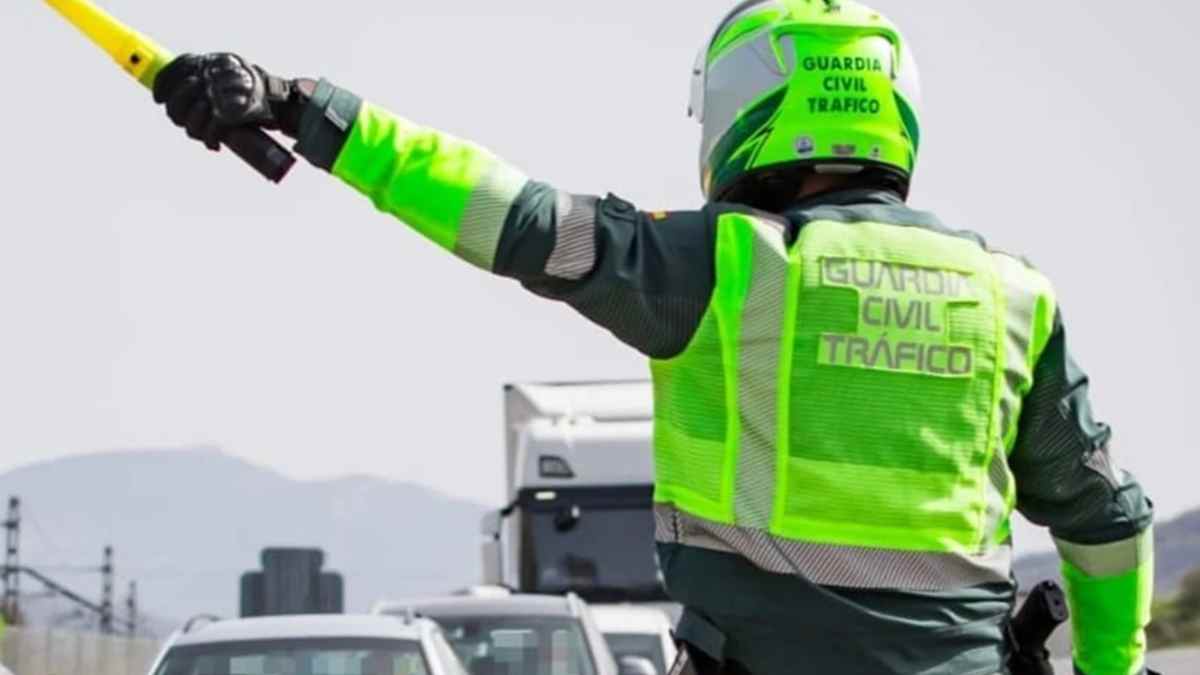 Agente de la Guardia Civil de Tráfico señalizando con banderín amarillo en carretera.