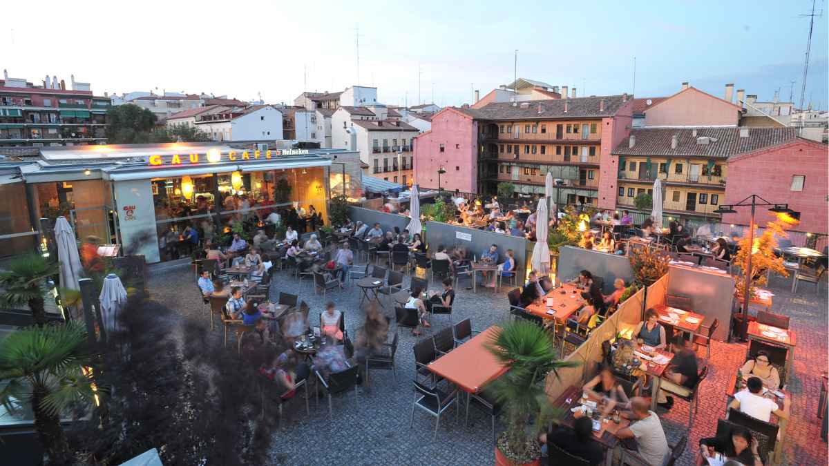 Terraza de un café en Lavapiés, Madrid, con clientes disfrutando de una noche de ocio en la zona de moda.