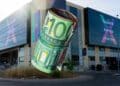Rollo de billetes de 100 € ante un centro de FP, simbolizando las becas de hasta 3.500 € en Madrid 2025-2026.
