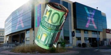 Rollo de billetes de 100 € ante un centro de FP, simbolizando las becas de hasta 3.500 € en Madrid 2025-2026.