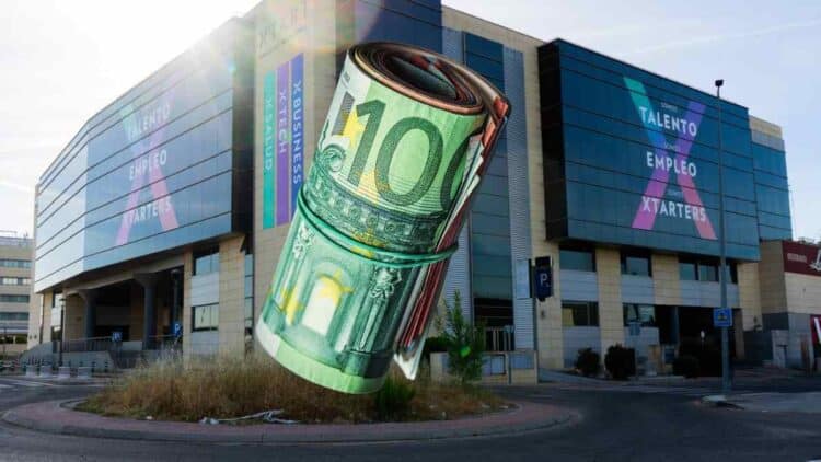 Rollo de billetes de 100 € ante un centro de FP, simbolizando las becas de hasta 3.500 € en Madrid 2025-2026.