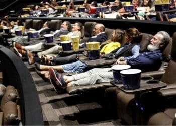 Personas mayores disfrutando de una película en un cine cómodo y con aire acondicionado en Madrid durante el verano.