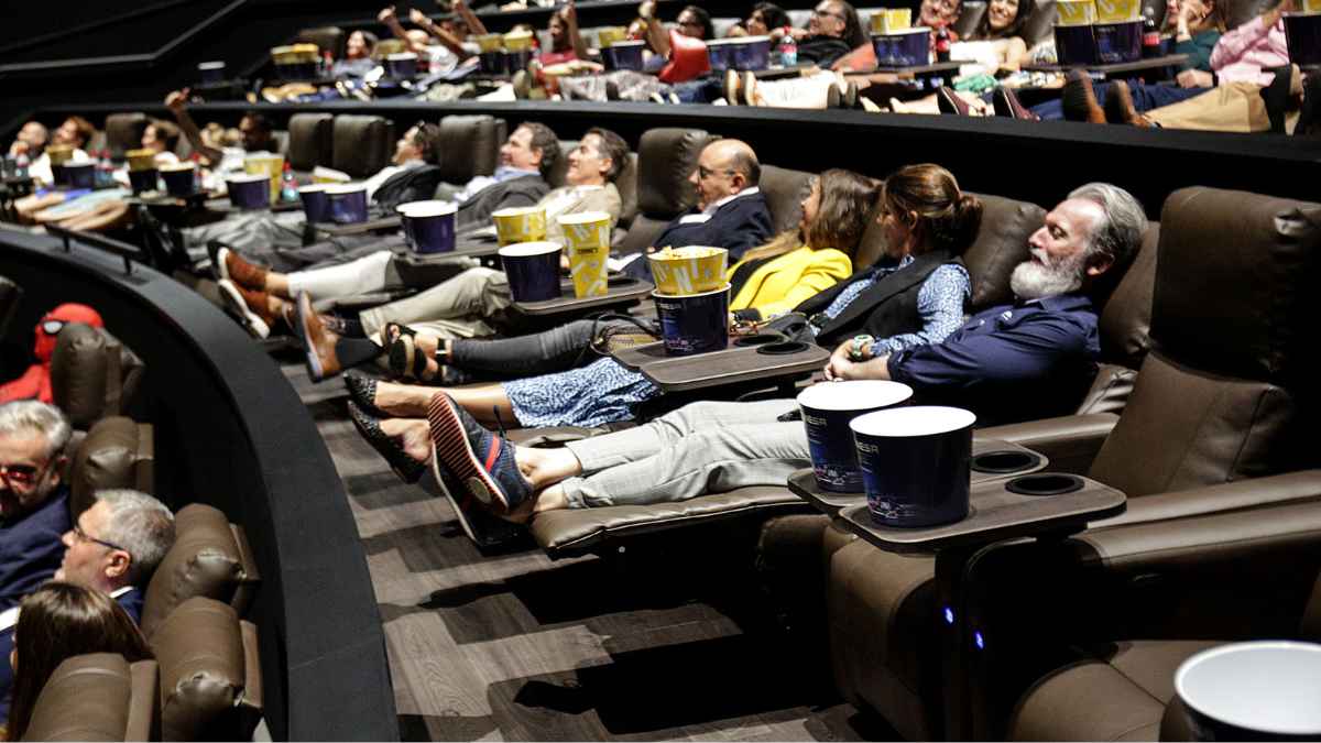 Personas mayores disfrutando de una película en un cine cómodo y con aire acondicionado en Madrid durante el verano.