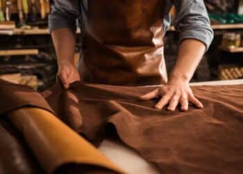 Artesano del cuero extiende una piel marrón para fabricar cinturones, botas y carteras, oficio en riesgo por la nueva norma europea.