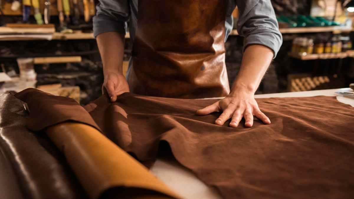 Artesano del cuero extiende una piel marrón para fabricar cinturones, botas y carteras, oficio en riesgo por la nueva norma europea.