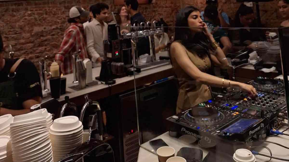 DJ pinchando en una coffee party en Madrid, con café de especialidad y público en una fiesta matinal saludable sin alcohol.