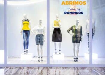 Escaparate de tienda abierta en domingo con cartel “Abrimos todos los domingos”, ejemplo de compensación por trabajar en festivo.