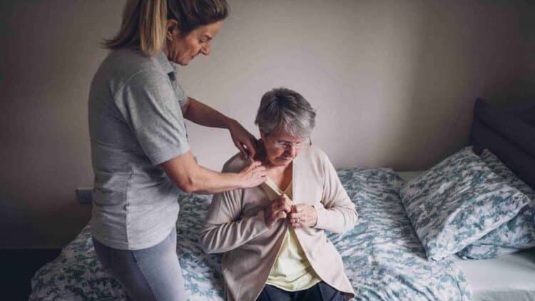 Asistente personal ayudando a persona mayor con dependencia en su hogar