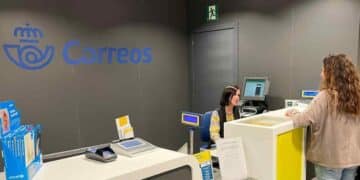 Empleada de Correos atiende a una cliente en la oficina postal.
