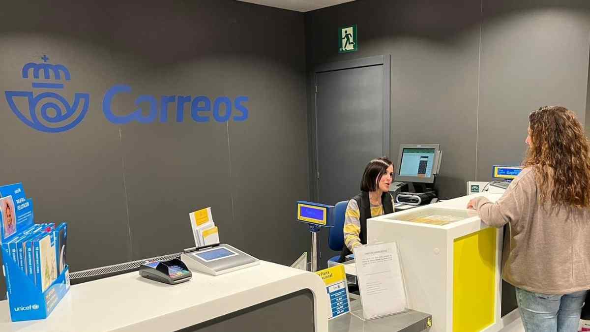 Empleada de Correos atiende a una cliente en la oficina postal.