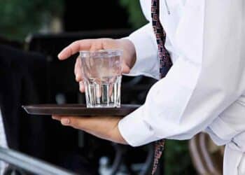 Camarero sirviendo vaso de agua del grifo en un bar de Madrid.