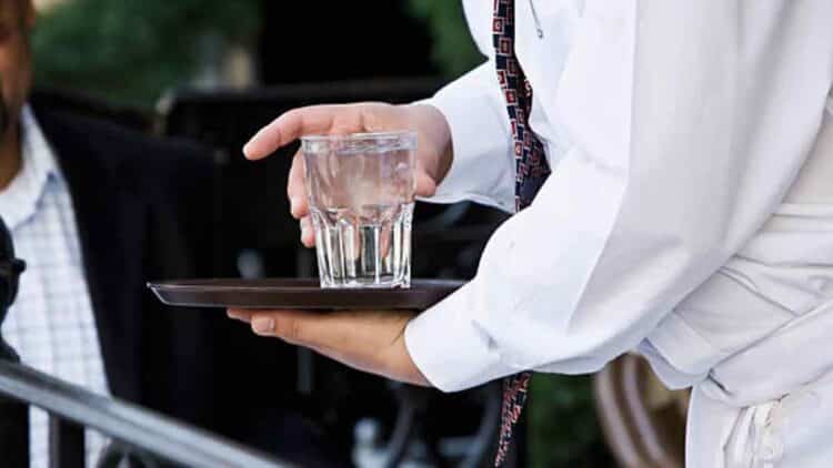 Camarero sirviendo vaso de agua del grifo en un bar de Madrid.