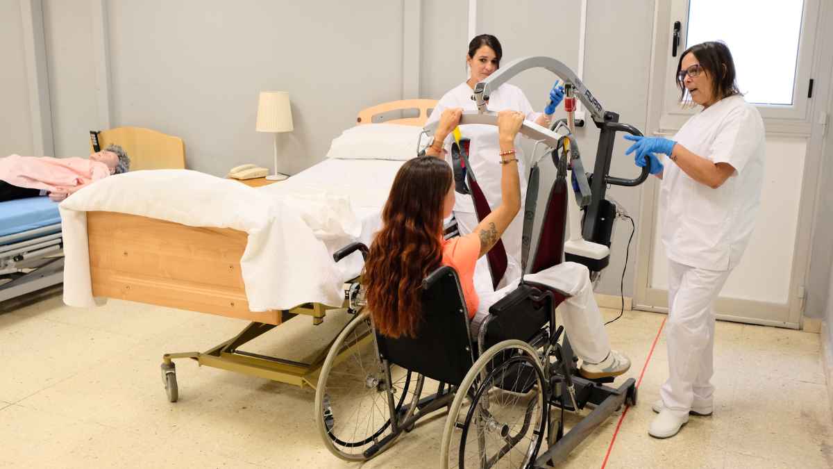 Formación en atención sociosanitaria, profesionales ayudando a un paciente con equipo de asistencia.