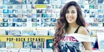 Interior de Discos La Metralleta en Madrid con mujer sonriendo junto a estanterías de vinilos y CD de pop-rock español.