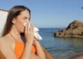 Mujer enferma en la playa estornudando durante sus vacaciones y con derecho a recuperar los días libres.