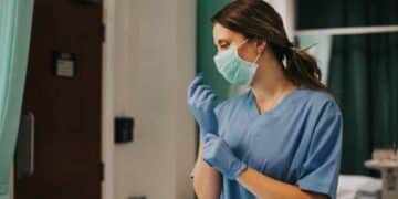 Enfermera francesa con mascarilla ajustándose los guantes en un hospital, noticia sobre devolución de 8.000 euros tras la jubilación.