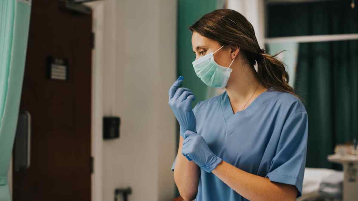 Enfermera francesa con mascarilla ajustándose los guantes en un hospital, noticia sobre devolución de 8.000 euros tras la jubilación.