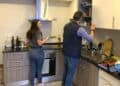 Dos estudiantes cocinan en la pequeña cocina de un piso compartido en Madrid ante la subida del alquiler universitario.