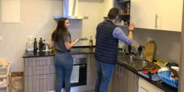 Dos estudiantes cocinan en la pequeña cocina de un piso compartido en Madrid ante la subida del alquiler universitario.