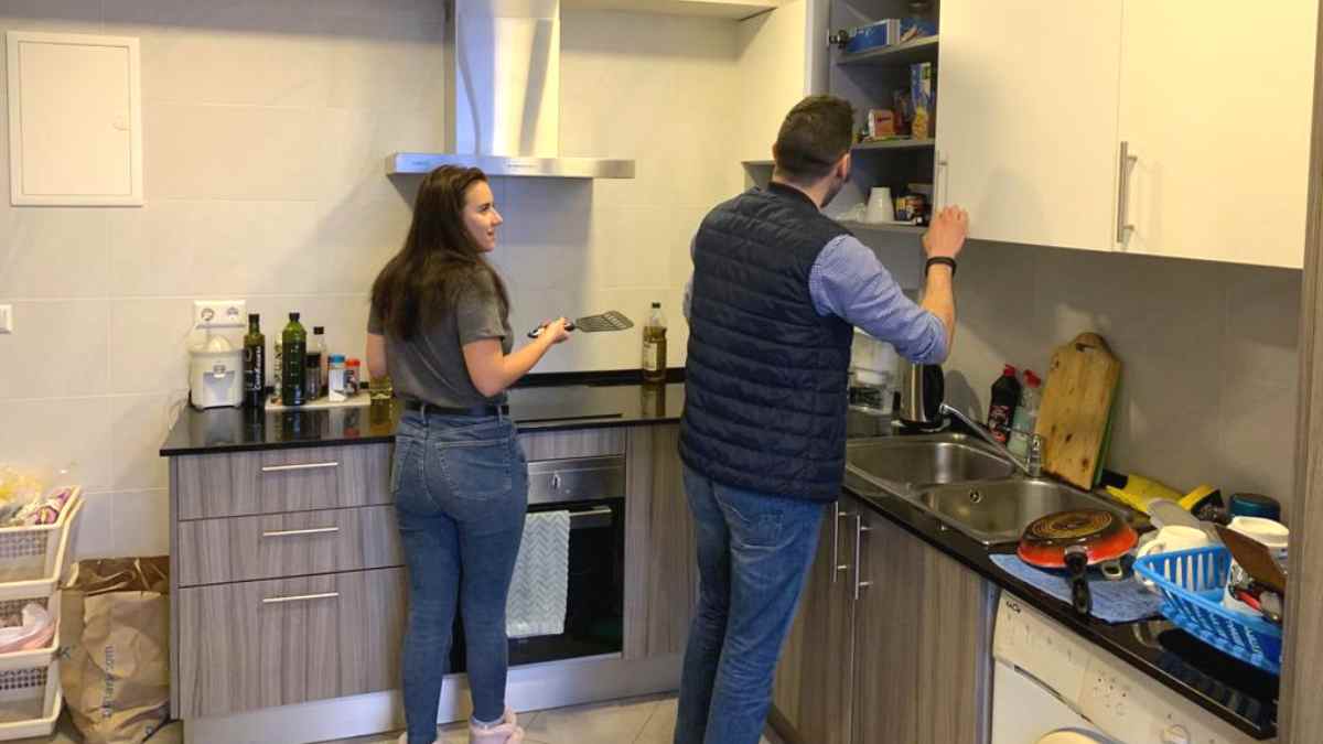 Dos estudiantes cocinan en la pequeña cocina de un piso compartido en Madrid ante la subida del alquiler universitario.