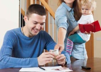Padre contando dinero junto a madre con bebé, familias que obtienen hasta 1.462 € de ayuda económica del Ingreso Mínimo Vital.