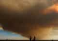 Columna de humo del incendio de Méntrida cubre la A-5 mientras varias personas observan el avance del fuego y la ceniza.