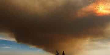 Columna de humo del incendio de Méntrida cubre la A-5 mientras varias personas observan el avance del fuego y la ceniza.