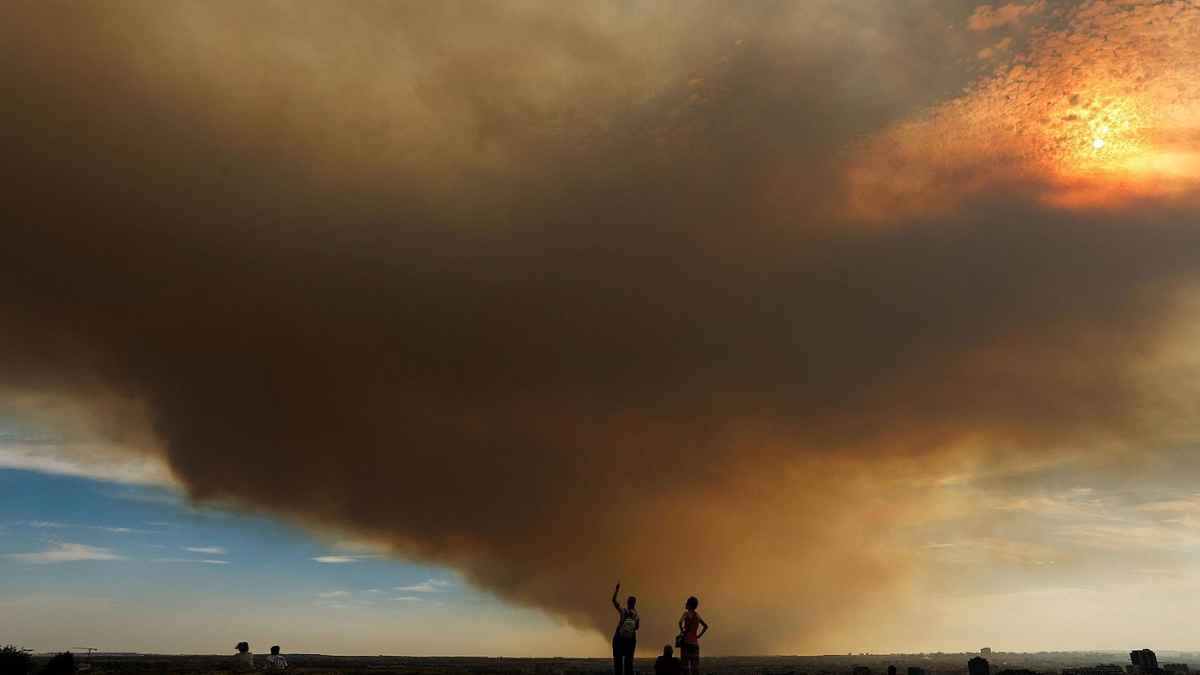 Columna de humo del incendio de Méntrida cubre la A-5 mientras varias personas observan el avance del fuego y la ceniza.