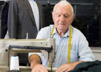 Hombre mayor trabajando en una máquina de coser, símbolo del retraso de la jubilación y de trabajar más años.