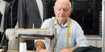 Hombre mayor trabajando en una máquina de coser, símbolo del retraso de la jubilación y de trabajar más años.