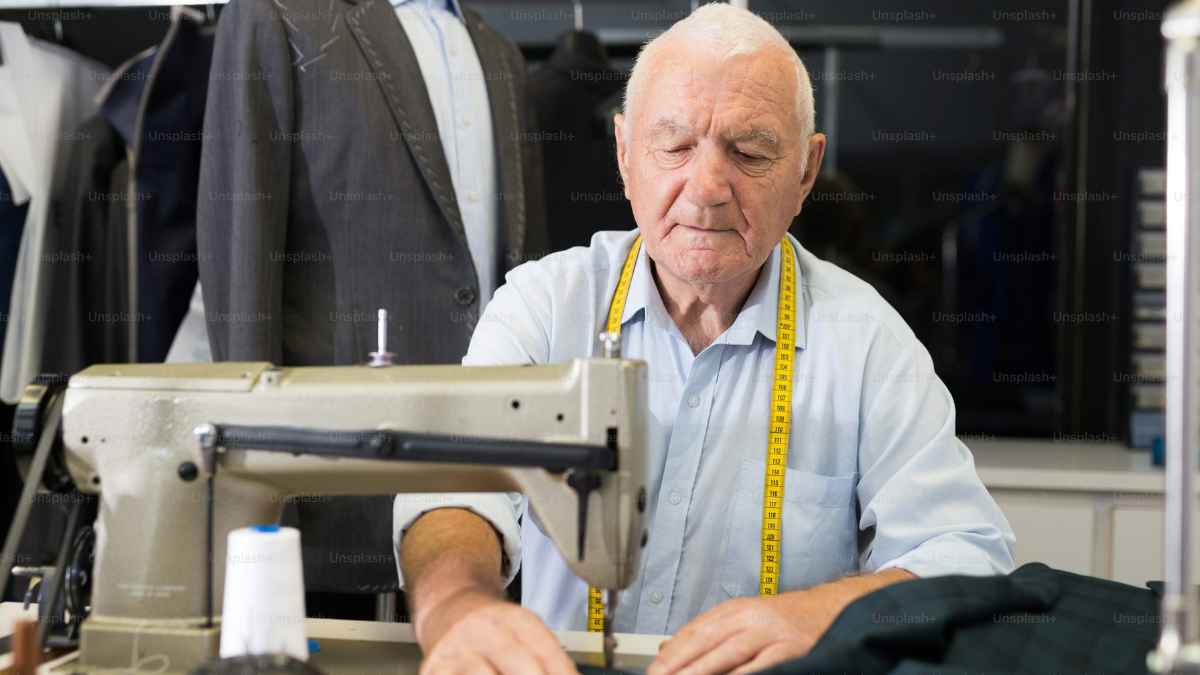 Hombre mayor trabajando en una máquina de coser, símbolo del retraso de la jubilación y de trabajar más años.