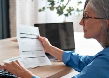 Mujer revisando documentos sobre los nuevos requisitos para jubilarse con pensión completa a los 63 años desde enero.