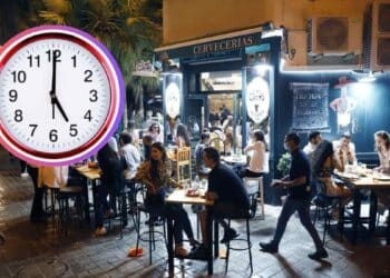 Terraza nocturna de un bar en Madrid llena de clientes, con un reloj marcando la medianoche que ilustra la ampliación de horario de cierre durante el Orgullo 2025.
