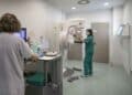 Profesionales sanitarios trabajando con mamógrafo en una consulta médica.