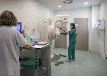 Profesionales sanitarios trabajando con mamógrafo en una consulta médica.