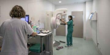 Profesionales sanitarios trabajando con mamógrafo en una consulta médica.