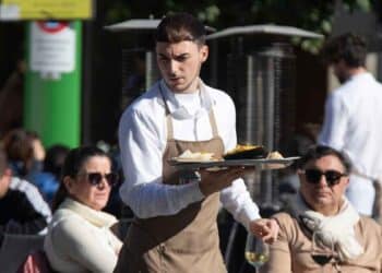 Camarero trabajando en una terraza, denuncia condiciones laborales oferta hostelería 1600 euros sin días libres.