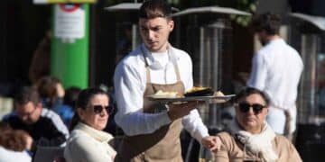 Camarero trabajando en una terraza, denuncia condiciones laborales oferta hostelería 1600 euros sin días libres.